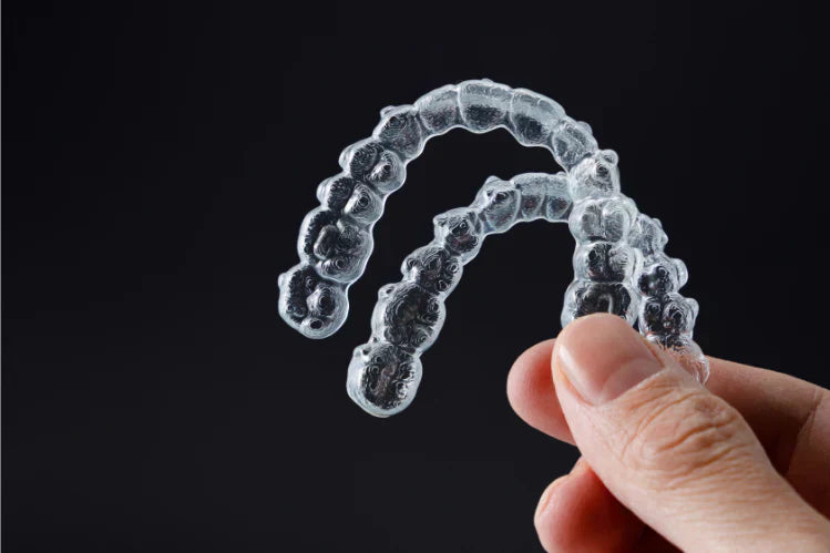 Una mano che tiene i fermi trasparenti per i denti superiori e inferiori