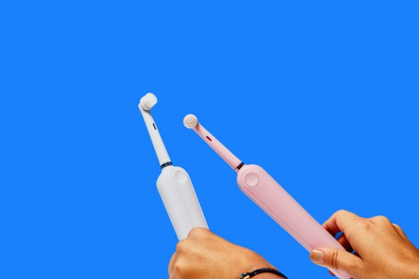 Spazzolini elettrici bianchi e rosa su sfondo blu