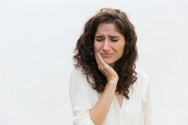 Una donna si tiene la mascella per il mal di denti.